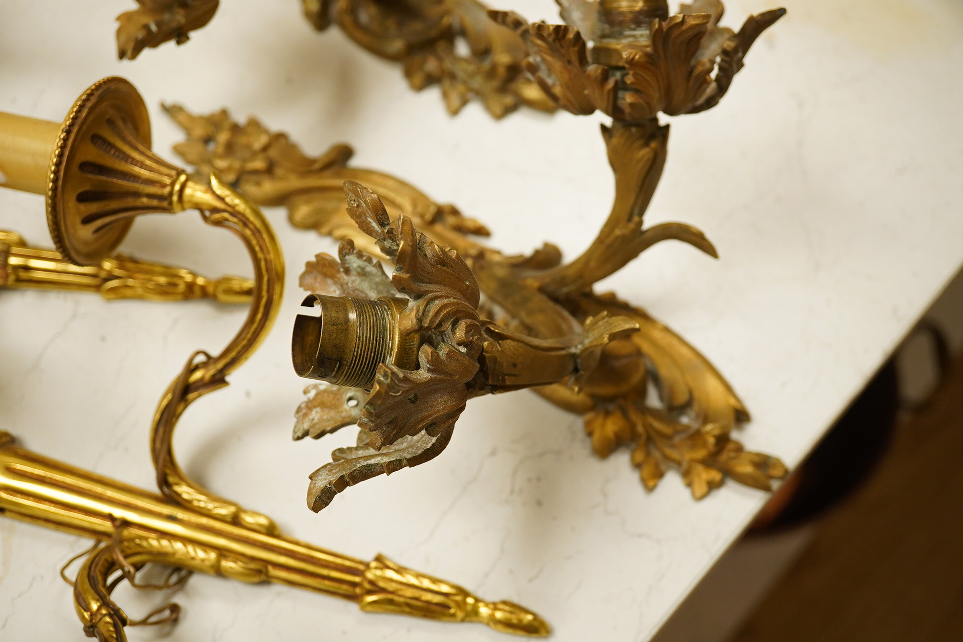 An ormolu ceiling light, a pair of three branch sconces and two pairs of two light sconces, largest 38cm high. Condition - variable